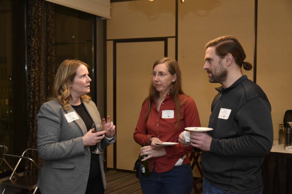 Three alumni talking together at the event.